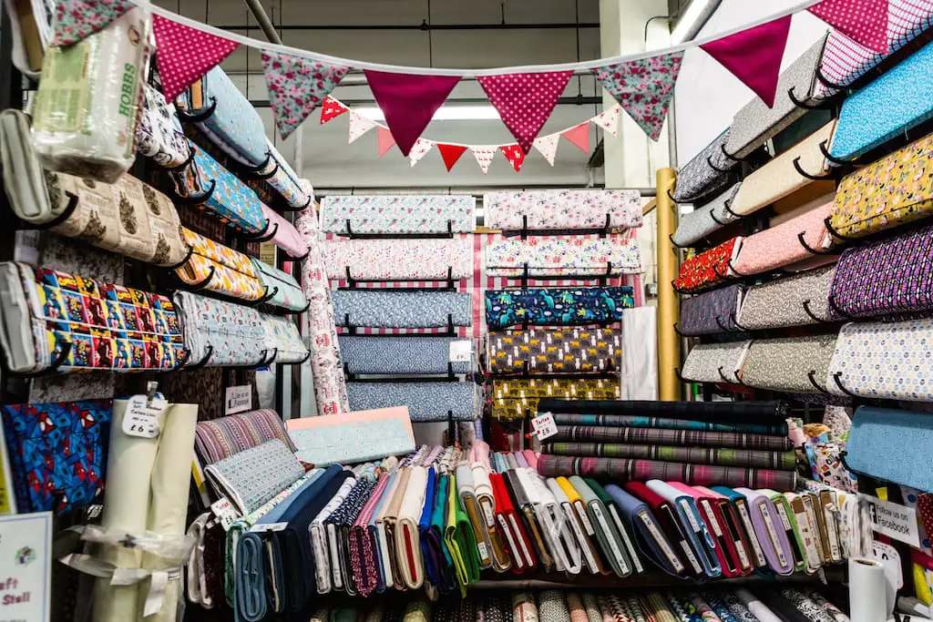Market stall filled with colourful fabrics and strewn with bunting