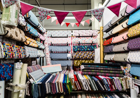 Market stall filled with colourful fabrics and strewn with bunting