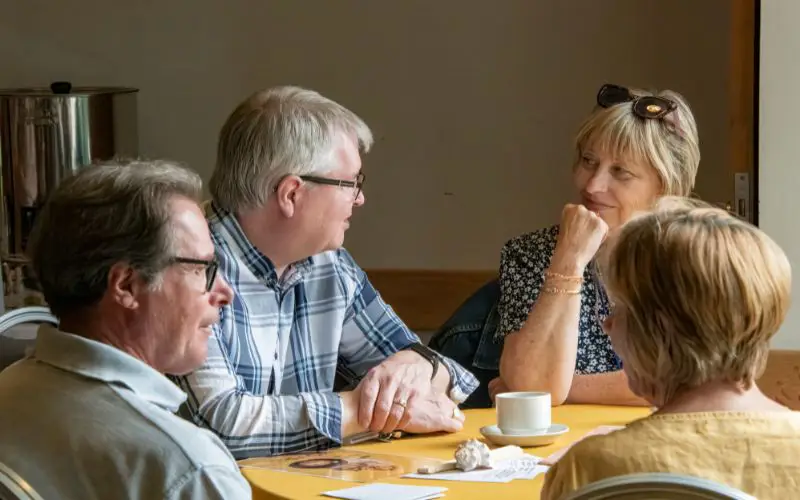 A group of people chatting, sat around a table. 