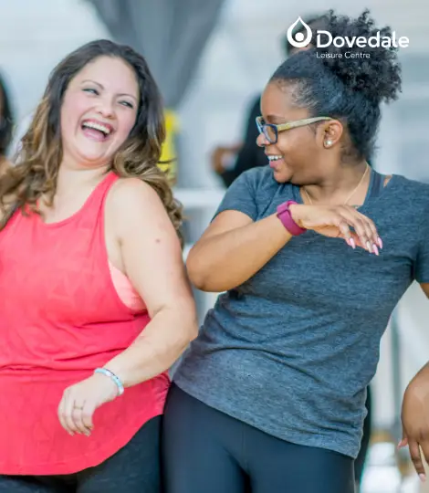 Two women in an exercise class smiling and laughing together