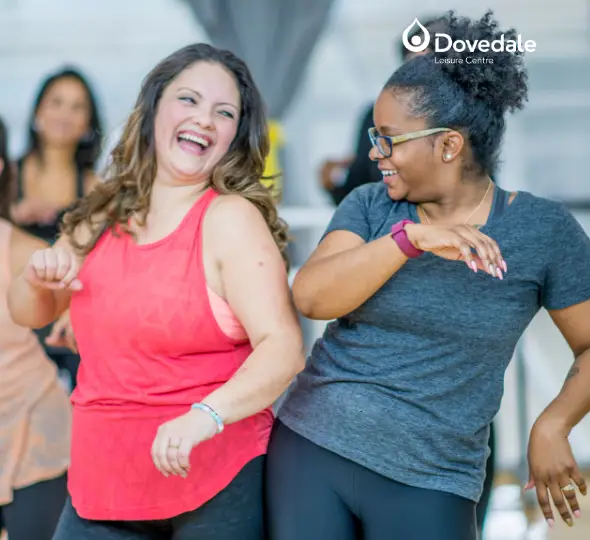 Two women in an exercise class smiling and laughing together