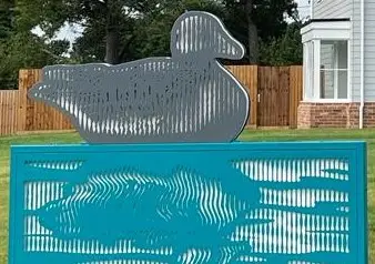 Large metal sculpture of goose with abstract reflective image below