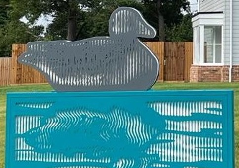 Large metal sculpture of goose with abstract reflective image below