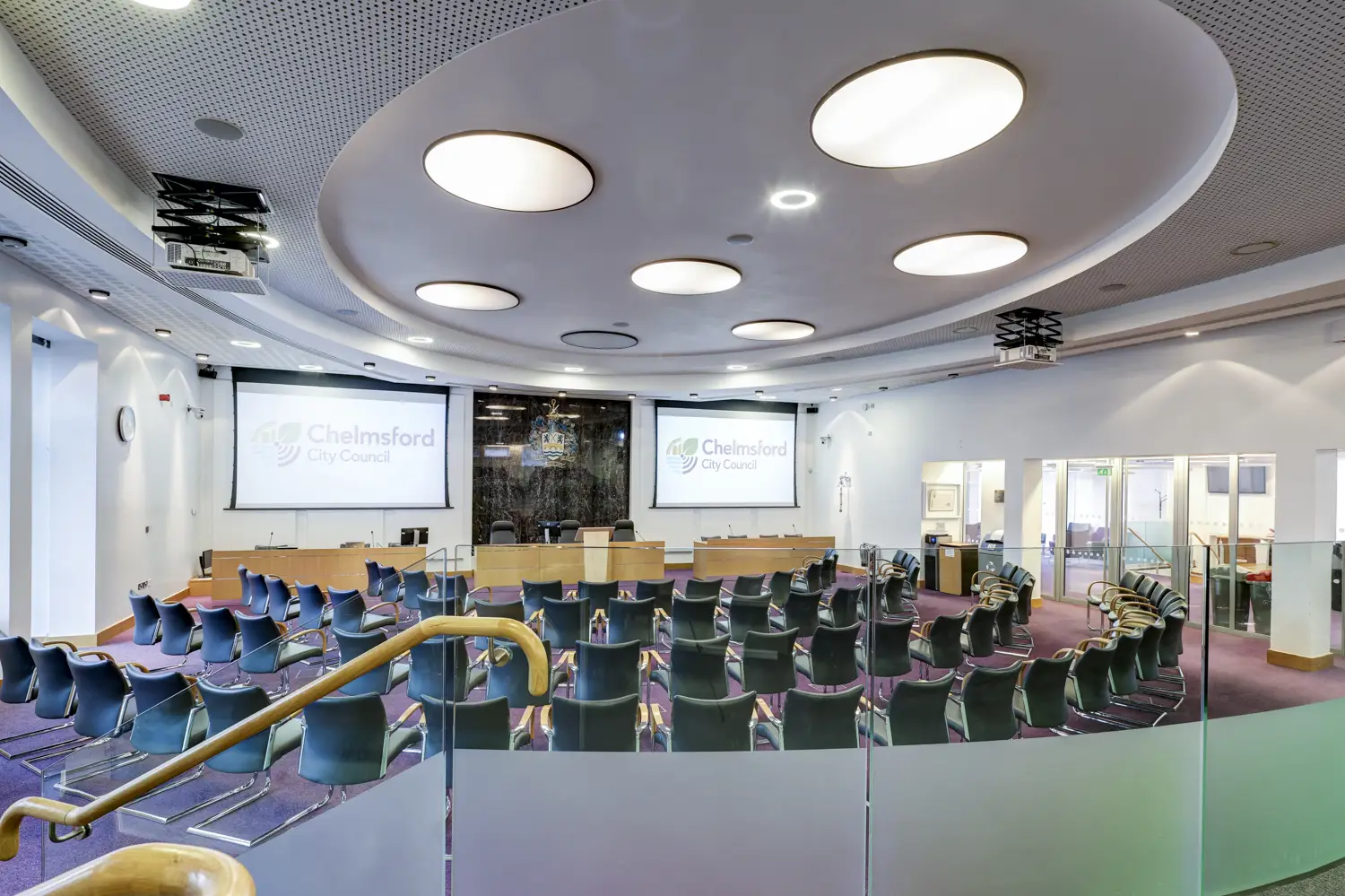 Large, well-lit room with plenty of chairs arranged to face big screens