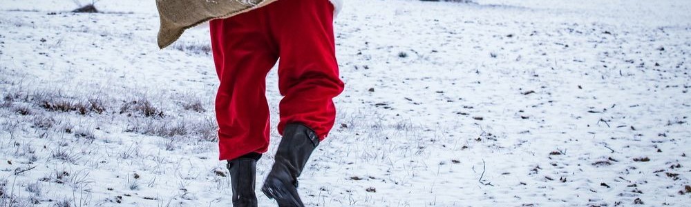 Santa figure carrying a sack and waling through the snow