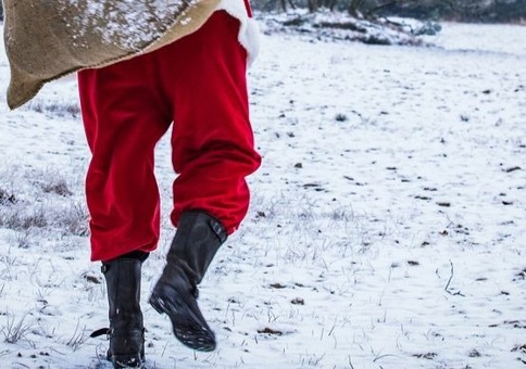 Santa figure carrying a sack and waling through the snow