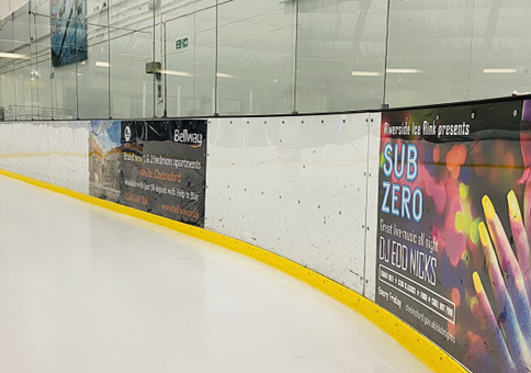 Adverts around the edge of the ice rink, with yellow strip marking the edge