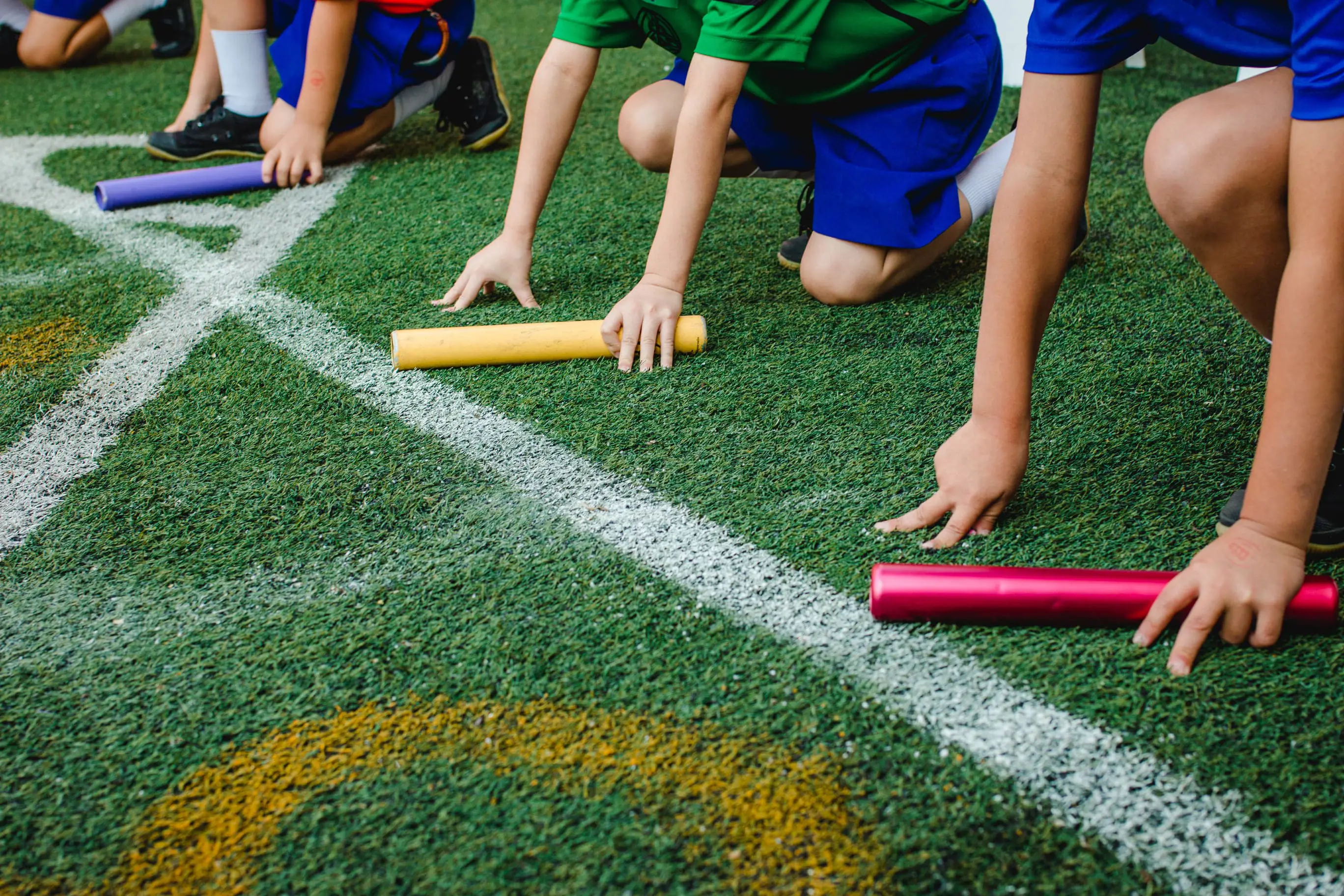 Children lining up at start line with batons ready to race