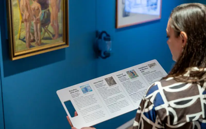 A woman looking at an information card in the Shifting Perspectives exhibition. 
