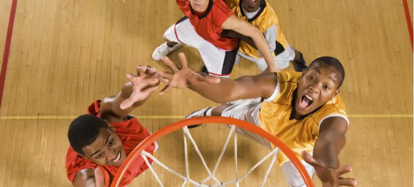 Basketball hoop seen from above with players reaching up
