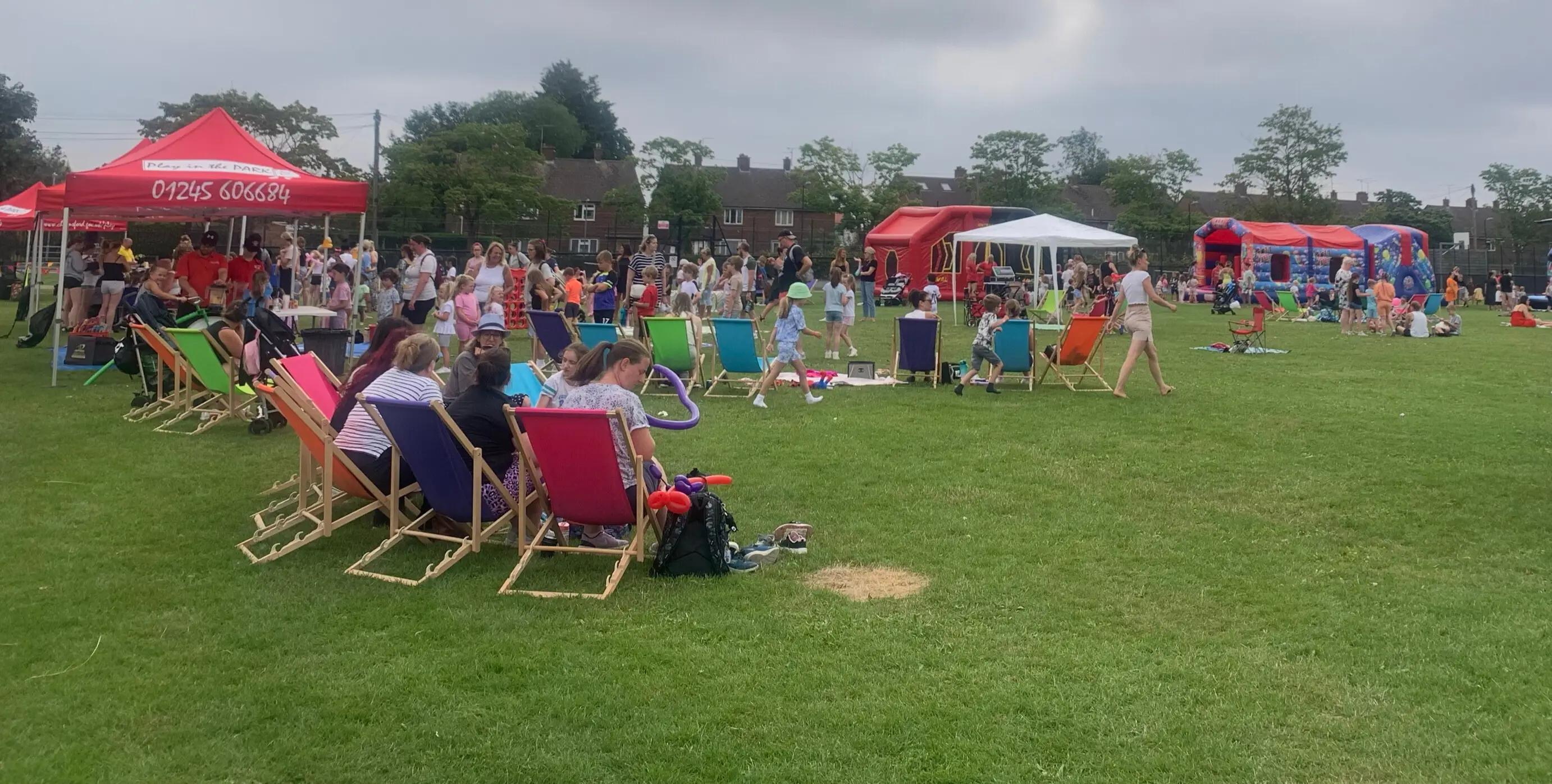 Lots of people in a park with gazebos and deckchairs having fun