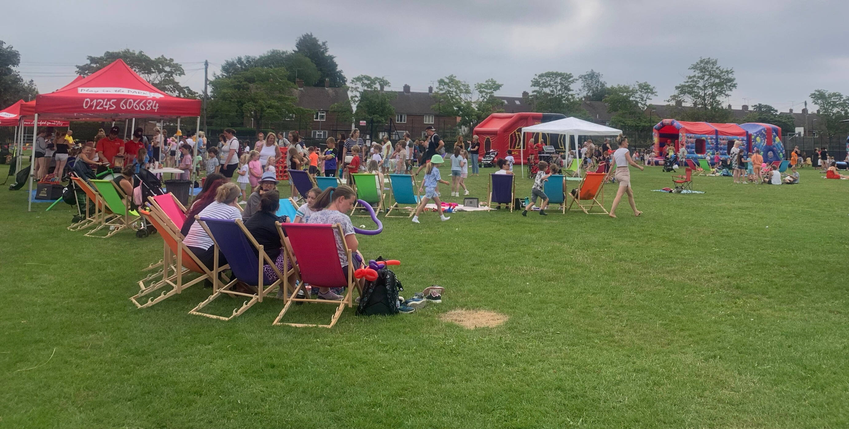 Lots of people in a park with gazebos and deckchairs having fun