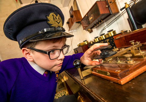 Young boy with a hat using a Morse code device. 