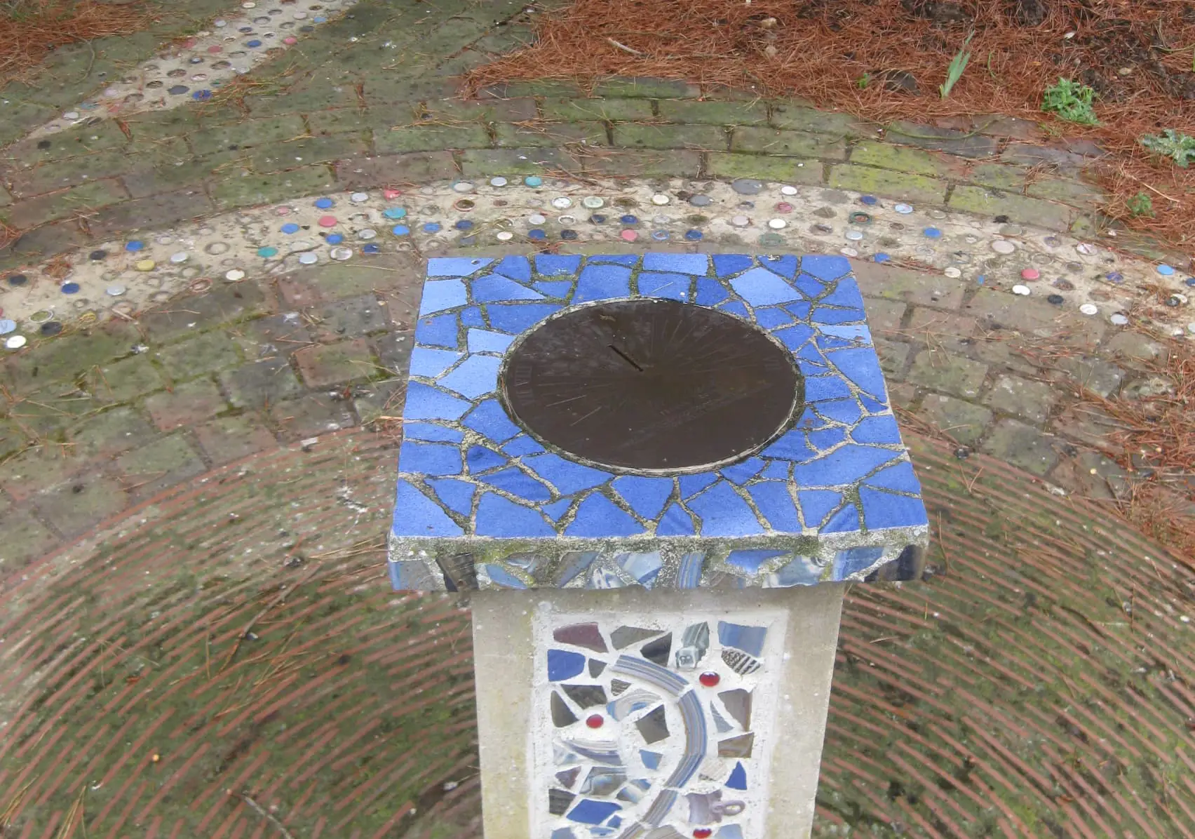 Stone plinth decorated with mosaic tiling, inside a mosaic circle