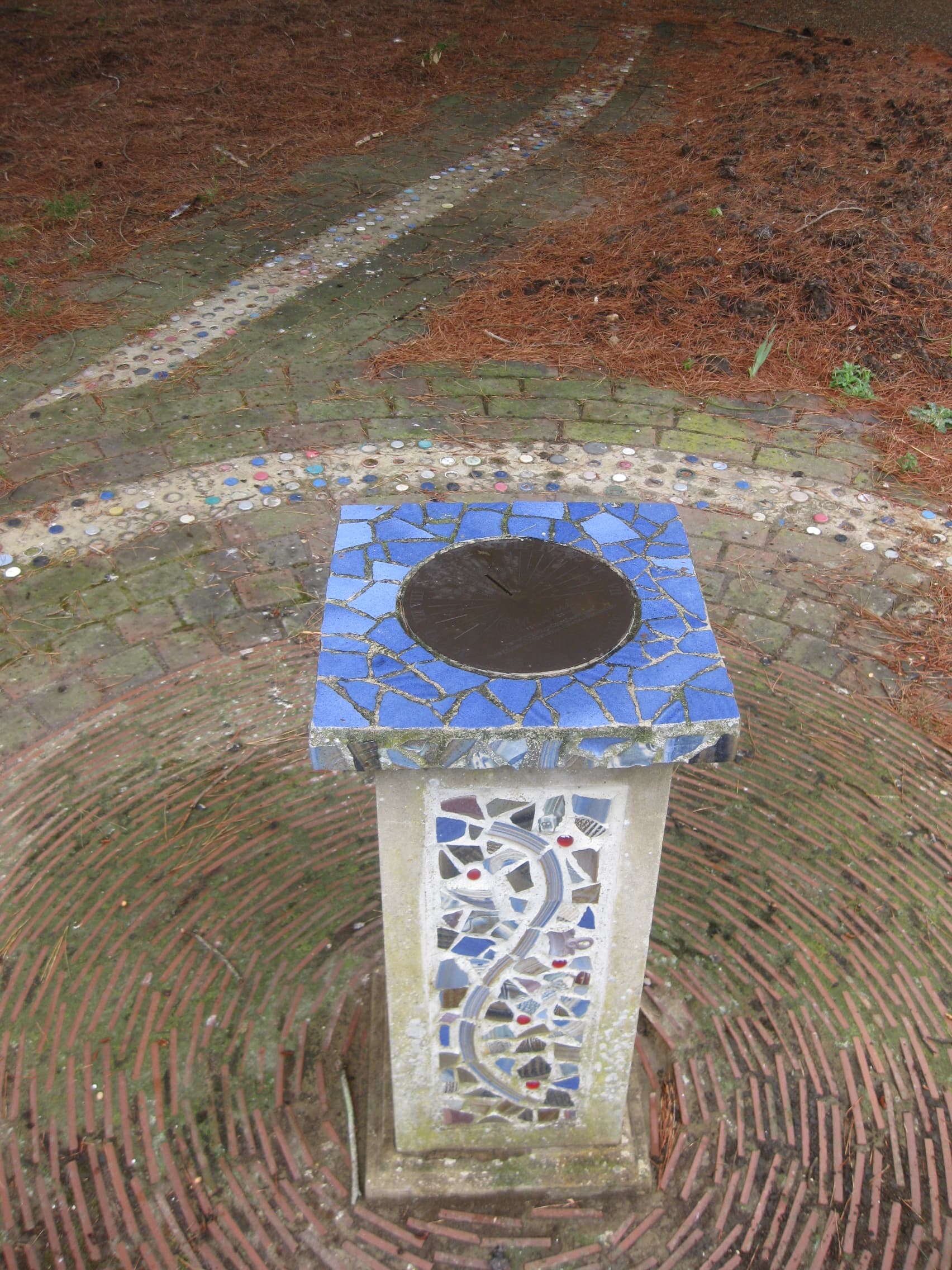 Stone plinth decorated with mosaic tiling, inside a mosaic circle