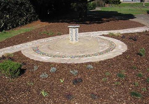 Stone plinth inside a mosaic circle surrounded by small plants
