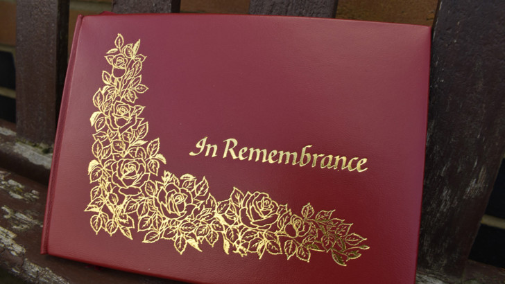 Red leather book with gold decoration and 'In Remembrance' lettering
