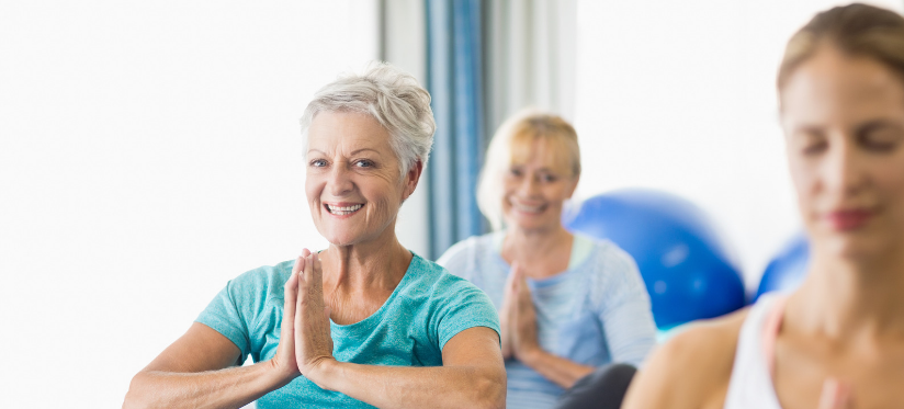 Smiling woman with hands in prayer in yoga class