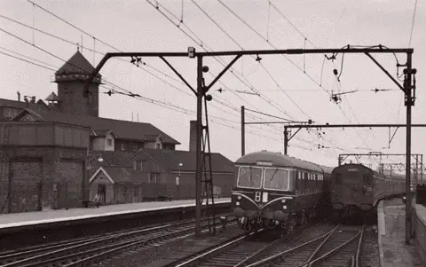 Chelmsford railway station, showing trains on tracks with mill and water tower behind  (Photograph courtesy and copyright © Stuart Axe)
