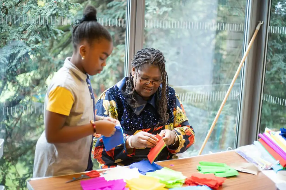 A lady teaching a young child to sew