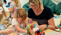 Woman and small girl making a crown in the craft tent preview