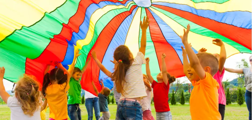Group of children playing with large multi-coloured parachute