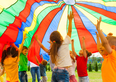 Group of children playing with large multi-coloured parachute