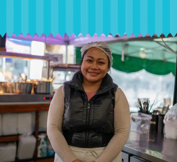 Smiling woman wearing hairnet at a food stall in Chelmsford Market