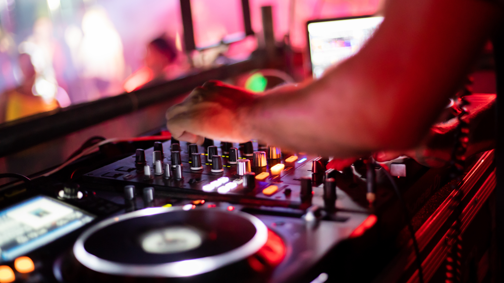A DJ's hand mixing music in a positive bright atmosphere.