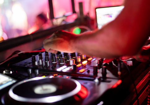 A DJ's hand mixing music in a positive bright atmosphere.