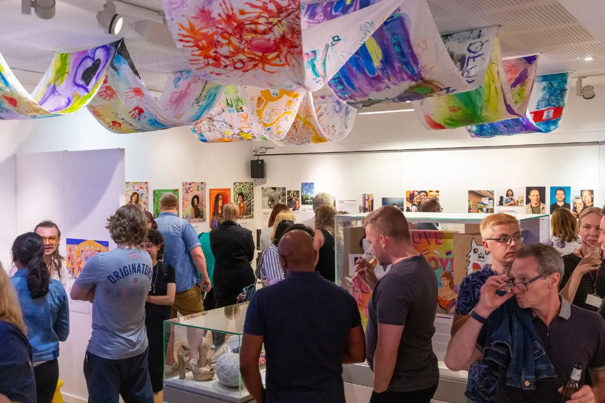 A crowd of visitors looking at displays at the Behind the Rainbow exhibition launch. 