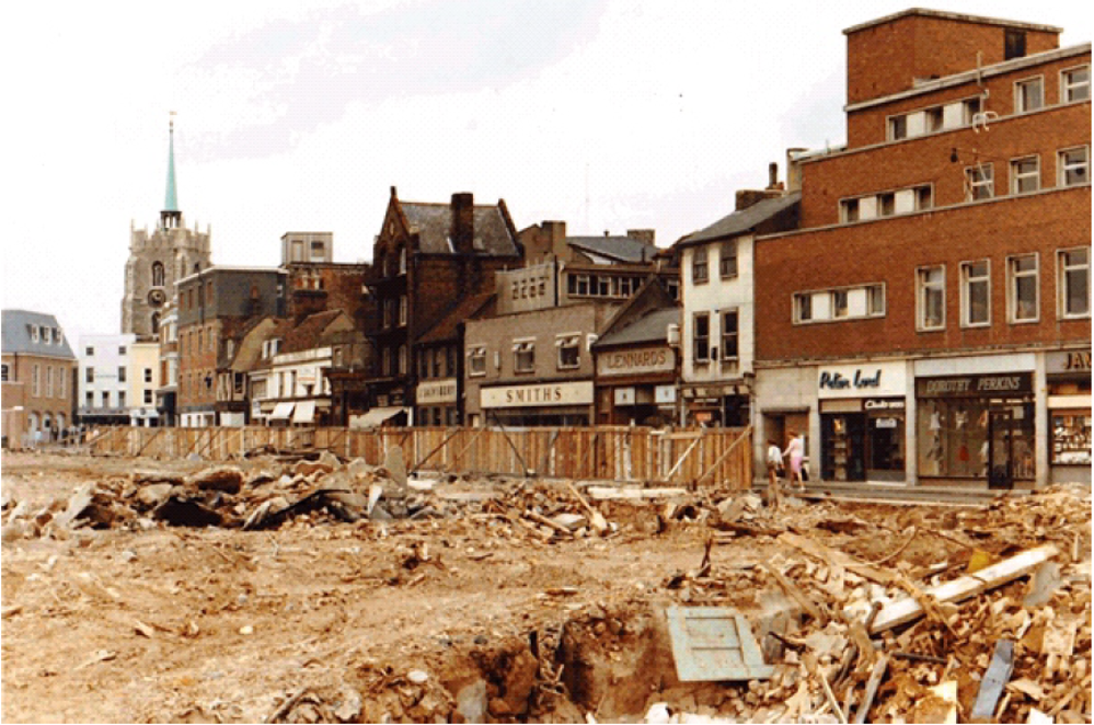 Row of shops with cathedral in the background, overlooking cleared site (which would become High Chelmer)