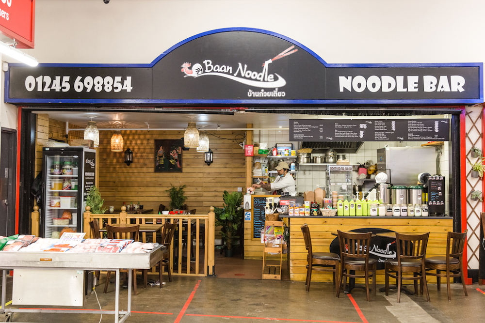 Noodle bar with tables and chair in front
