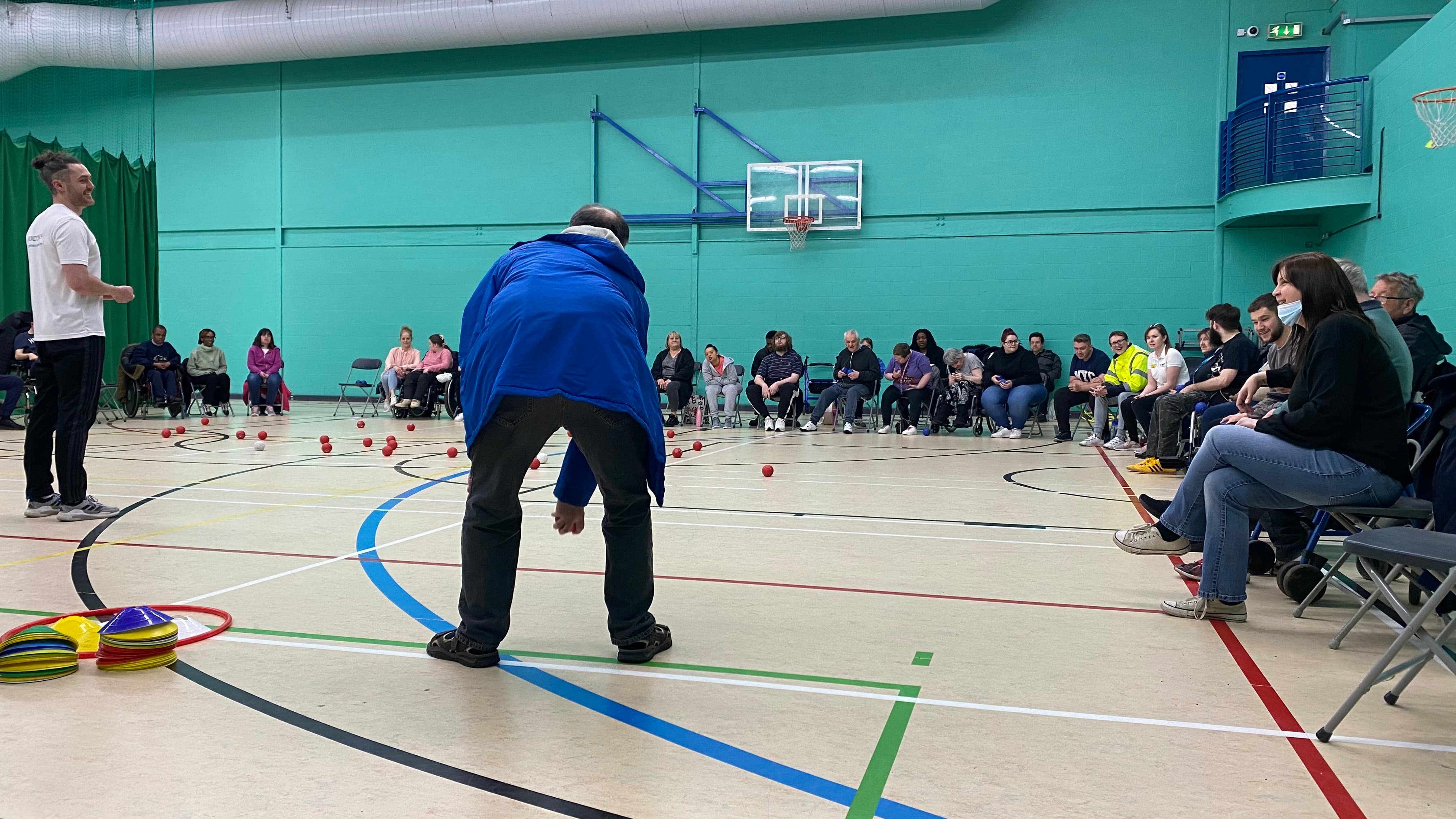 Man leaning over to throw a boccia ball