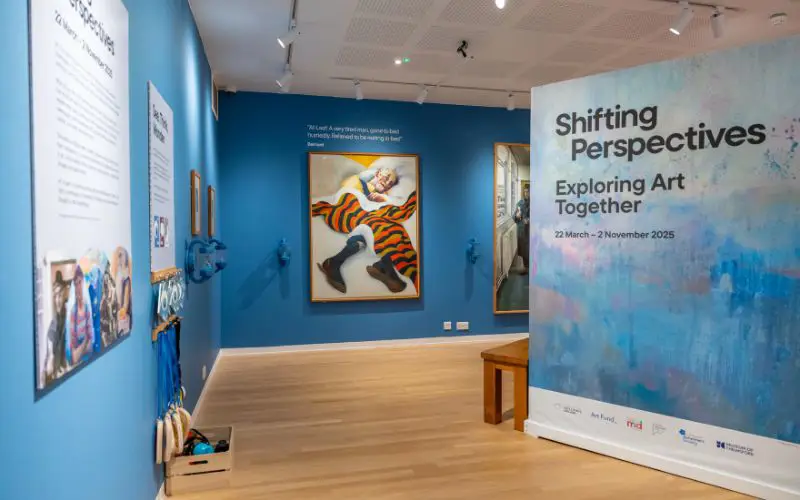 The Shifting Perspectives exhibition with bright blue walls and artwork on display.