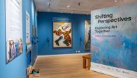 The Shifting Perspectives exhibition with bright blue walls and artwork on display.  preview