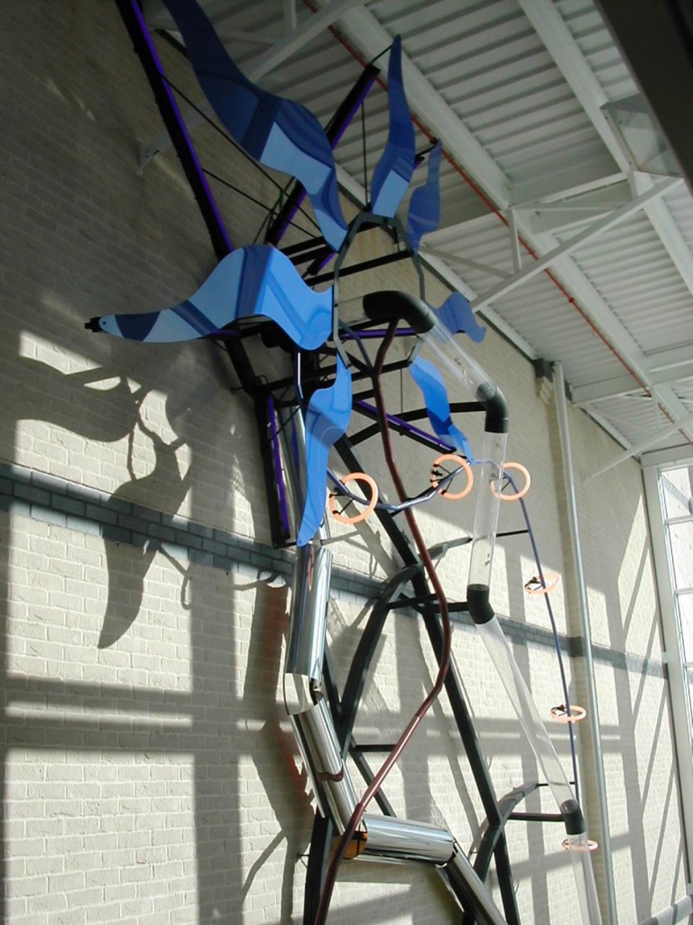 Sculpture of a large blue clock-like windmill on the side of a building