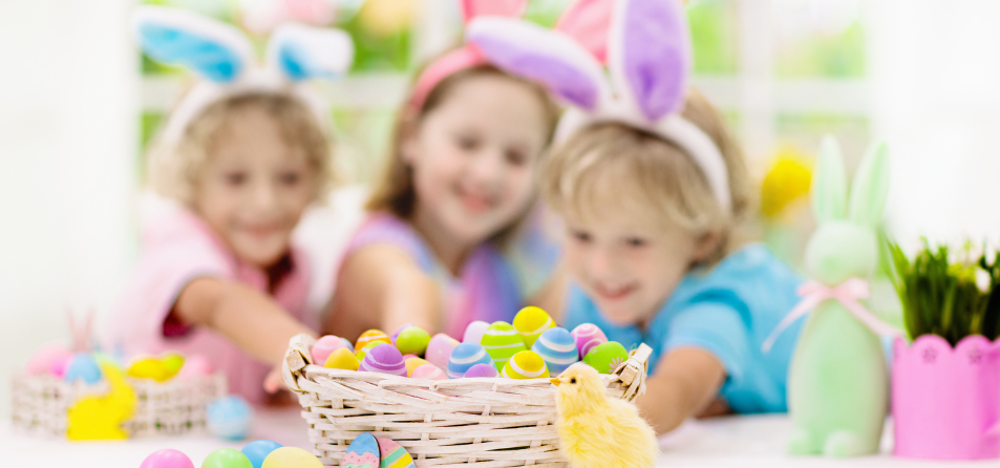 Children at an Easter party reaching out to a mini basket full of mini Easter eggs.