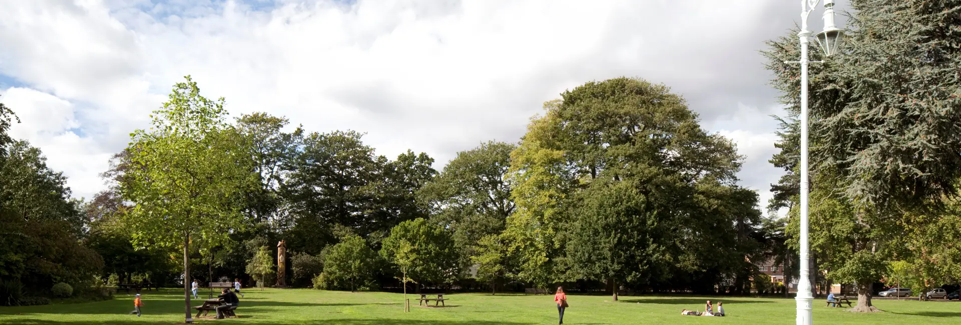 Green space with trees and benches and people walking