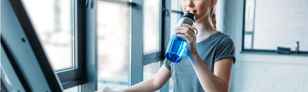 Younger teen girl sipping water on treadmill