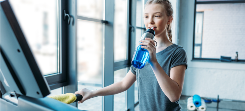 Younger teen girl sipping water on treadmill