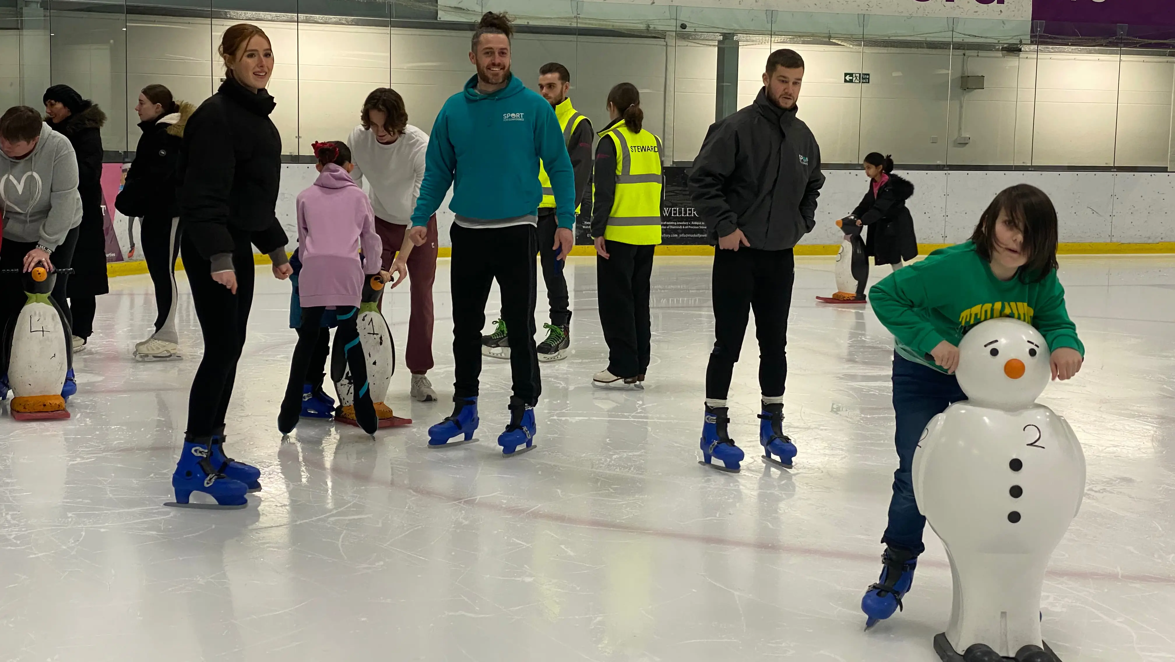 Coaches watching a child learn to ice skate