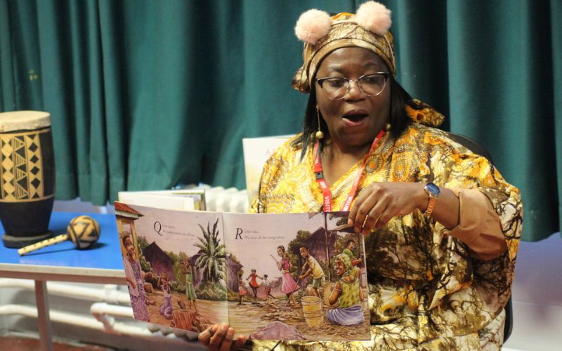 Storyteller Sade Fadipe holding up a children's book. 