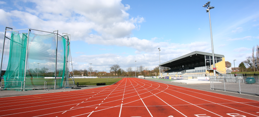 Athletics track at CSAC as seen from start line, with grandstand and throwing cage in the distance
