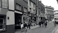 People walking past row of shops (black and white photo from 1958) preview