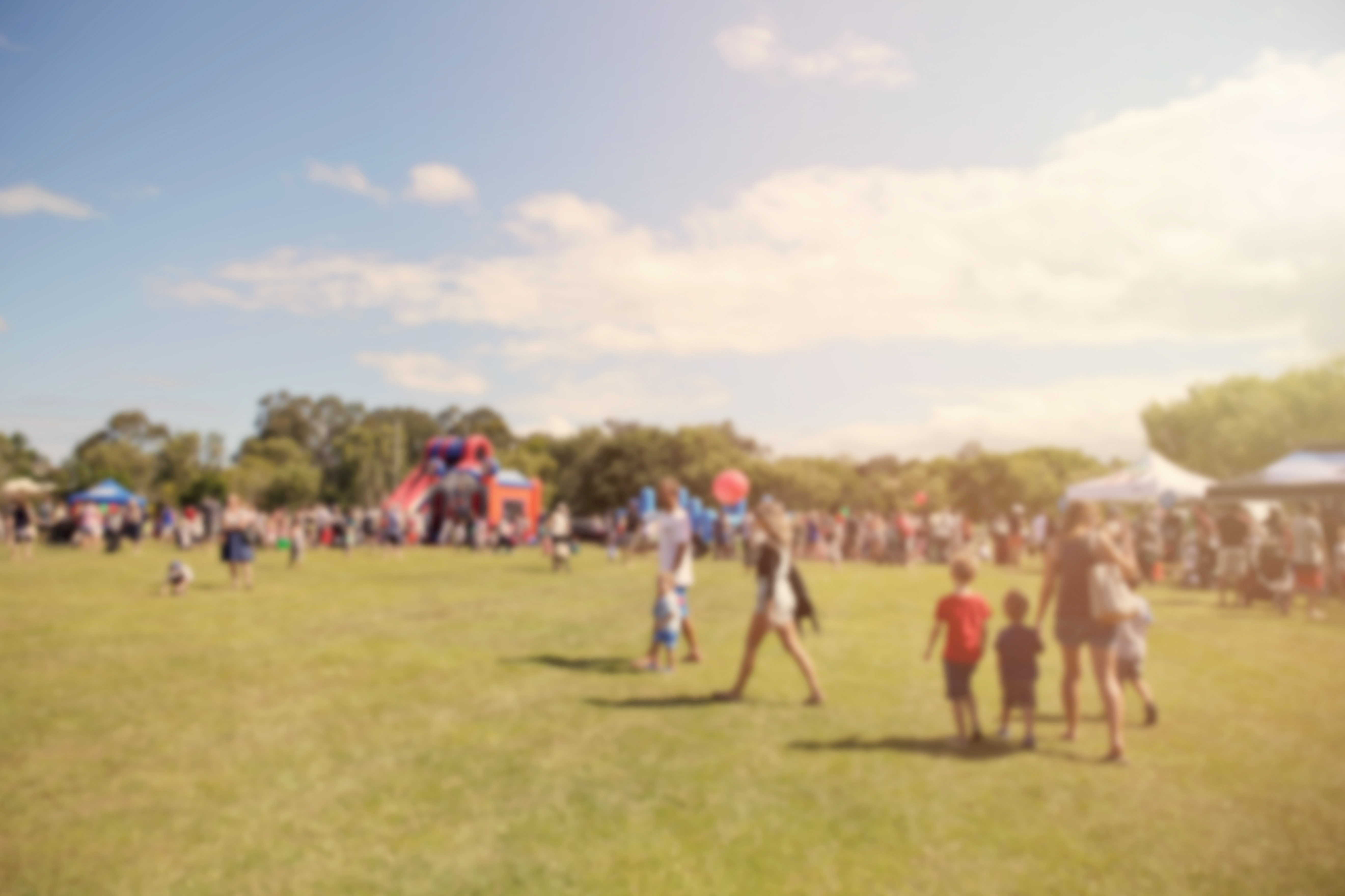 Field full of people enjoying family friendly festival in hazy sunshine