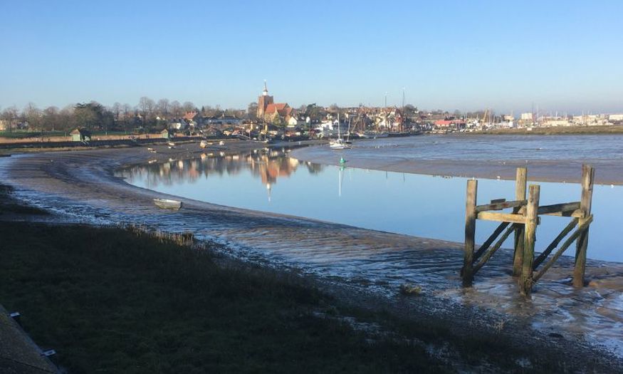A seaside town where the coast is curved. Boats can be seen in the shallow water. 