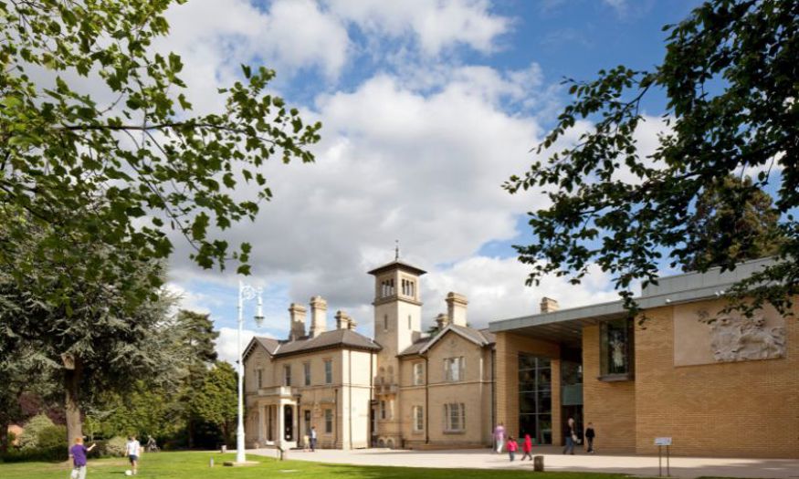 The exterior of Chelmsford Museum with visitors playing on the front lawn. 