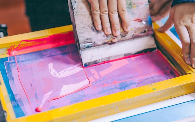 A close up of hands making a screen printing. 