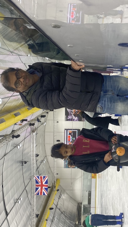 Father and daughter learning to ice skate, smiling.
